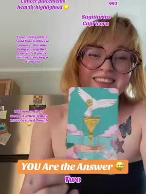 A selfie-style shot of a woman with glasses and blonde hair. She is smiling and holding a card with a white dove on it. Text overlays are present, including phrases about astrological placements and a call to action.