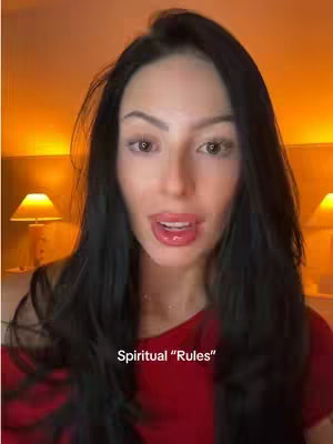 The cover image features a close-up of a woman's face. She has long, dark hair framing her face, and she is wearing a red top. The background appears to be an out-of-focus warm-toned room. The woman has her mouth open slightly, as if she is speaking. Overlayed text near the center bottom of the frame reads 'Spiritual “Rules”.'