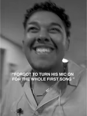 A black and white photo captures a close-up of a smiling man against a blurred backdrop. The man has curly hair, and is wearing a shirt with a silver necklace. Overlayed text reveals part of a funny story.