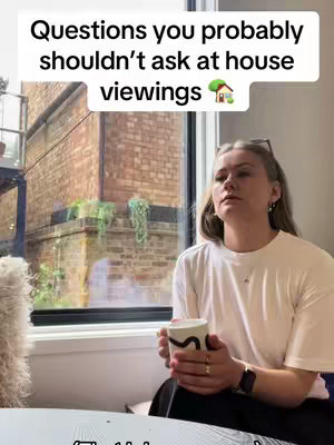 A woman with blonde hair is seated in front of a window, holding a mug with a design and looking off to the side. The window displays a brick building and greenery outside. Above the woman is a white rectangular overlay with text.