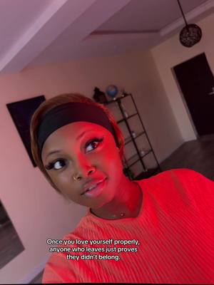 The image shows a woman looking directly at the viewer with a slightly upward gaze. She wears a black headband, and her short hair is styled with a natural color. Her skin tone is well-lit, with a noticeable red glow. She's wearing a red shirt. A caption is overlaid on the image.