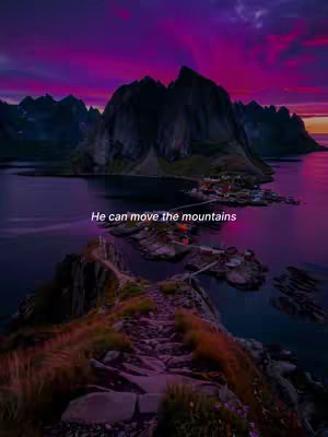 A landscape photo featuring a striking mountain range against a backdrop of a vibrant, multi-colored sunset. A body of water reflects the sky and mountains, and a stone path in the foreground leads to a small group of buildings.