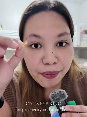 A woman holding a ring, with text overlayed that says CAT'S EYE RING for prosperity and abundance.