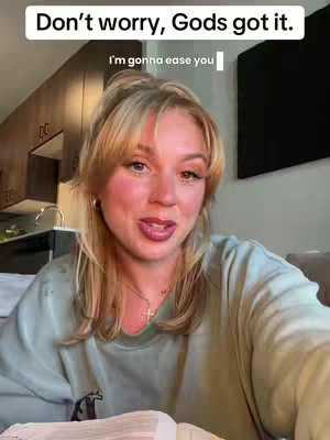 A woman with blonde hair and a light green sweater is centered in the frame, appearing to be filming in her home. Light from a window illuminates her face, and the background has kitchen cabinets and a television. Text overlays at the top and center of the frame.