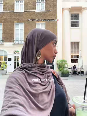 A woman in a gray hijab and black top poses for a selfie outdoors. The background includes pillars of a building and portions of another building. The woman is holding a drink in one hand. Text overlays the scene, including "POV: to my future husband." and "And it ain't right."