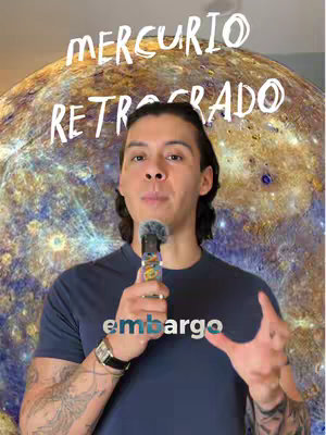 A man with long dark hair stands in front of a blurred image of what appears to be a planet, possibly Mercury. The man, wearing a navy blue t-shirt with the word "embargo" printed on it, is holding a microphone and gesturing with his right hand outwards. Above him, the text "MERCURIO RETROGRADO" is written in a bold, clean white font.