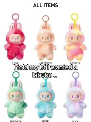 The image is a product display showcasing six colorful Labubu figurines. They are plush toys resembling small creatures with round faces and elongated ears, each in a different color: red, orange, yellow-pink, green, blue and white-purple. The positioning is such that they are aligned in two rows of three, and above the figures are the words 'ALL ITEMS', and below each one a color labeled as 'LOVE', 'HAPPINESS', 'LOYALTY', 'SERENITY', 'HOPE', and 'LUCK'. Below the figurines is the text: 'I told my bf I wanted a labubu ..'. The background is plain white.
