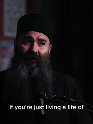 The image shows a man with a beard and a black hat in a dark room. The man is looking up and to the right, and below him is a text overlay.