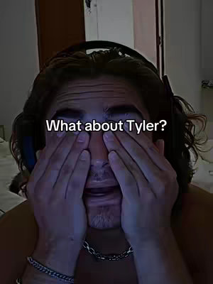 A person with long, dark hair and a silver chain necklace is shown in a close-up, covering their face with both hands, with an expression of distress or shock. The background is dimly lit, with a headset visible at the top, and a light-colored wall.