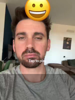 A selfie-style video cover with a man in the foreground. He's wearing a grey shirt and has a short beard. A yellow smiley face emoji is placed on top of his head. The background is a room with neutral tones and a painting on the wall.