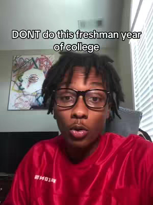 A young man with dreadlocks and glasses is looking at the camera. Above his head is the text overlay, "DONT do this freshman year of college". Behind them is a collage picture on the wall.