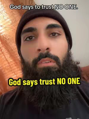 A man with a dark beanie and a thick beard is centered. Overlays contain quotations. The background is an orange curtain and a pale wall.