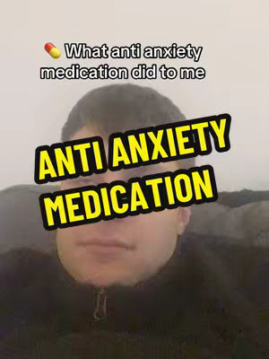 A selfie-style image featuring a young man in a black zip-up jacket, centered in the frame. Overlaid on his face is a large, yellow-and-black text box that reads 'ANTI ANXIETY MEDICATION'. Above the man’s head, there is another smaller text overlay reading '💊What anti anxiety medication did to me'. The background is a solid, light color that could be a wall or a neutral space.