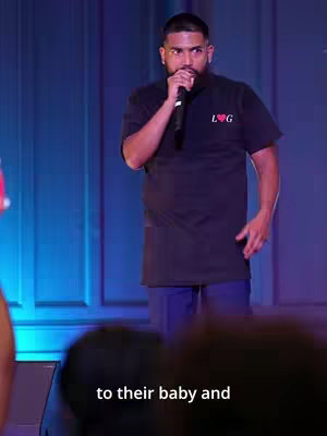 The cover image shows a man on stage holding a microphone. He is wearing a black t-shirt with a logo that has an "L" and a "G" with a heart in the middle. In the background, there are curtains and stage lighting.