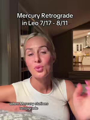 A woman with blonde hair is in the foreground, speaking to the camera. Text overlays at the top indicate a topic about Mercury Retrograde. The background is slightly out of focus, showing a kitchen and the corner of a room.