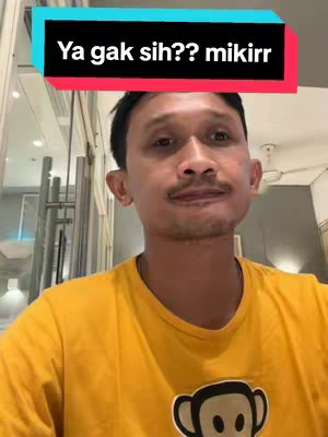 The cover image features a man in a yellow shirt looking at the camera. Above him is a rectangular text overlay with the words "Ya gak sih?? mikirr" in a black font against a cyan and red background. The background is blurred, possibly an interior space.