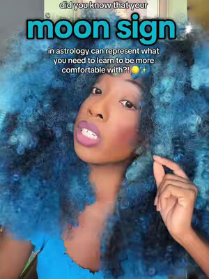 A selfie featuring a woman with vibrant blue afro hair and bright makeup. The woman is smiling and holding a finger towards her mouth. Overlaid text includes a title about moon signs. The overall composition centers on her face, set against a blurred, green background.