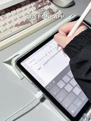 A person is shown working on an iPad placed on a desk alongside a keyboard and mouse. The person's hand, holding a white stylus, is visible as they write on the screen of the tablet. The image has a bright, clean aesthetic with a focus on the tech setup. The text overlay reads, "i don't, i use JUST ONE APP."