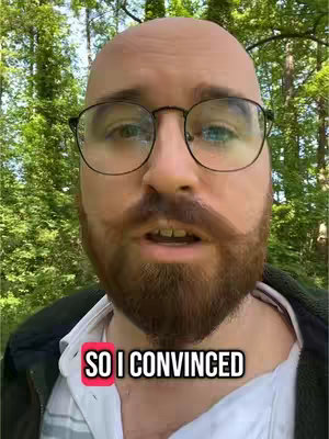 A close-up shot of a man with glasses, a beard, and a bald head. He appears to be outside in a green, natural setting. Text overlayed on the image reads, “SO I CONVINCED.”