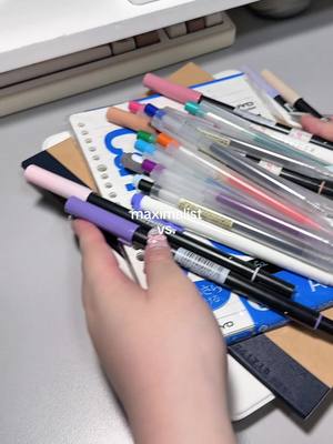 A hand holds a bundle of notebooks and pens on a table, with text overlayed in the center.