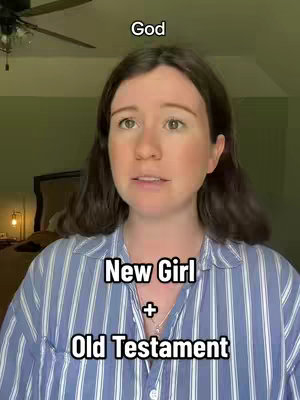 A woman with long, dark hair is centered in a selfie-style video against a green and beige background. She wears a striped button-down shirt, and text overlays are positioned on the image.  Above her head is the word 'God' and below her chest are the words and symbols 'New Girl' '+' 'Old Testament'. The background is a room with what could be a bed and lamp.