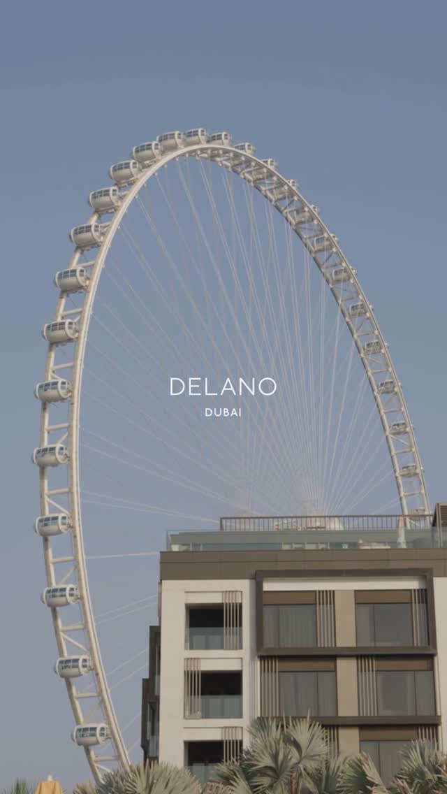The cover image shows a large white Ferris wheel in front of a building under a clear blue sky. The Ferris wheel is the main focus, positioned on the left side of the image. Below the Ferris wheel is a modern building with glass windows and a flat roof. The image is well-lit, with the sky providing a bright, clear background.