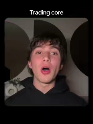 A selfie-style video cover featuring a young man with dark hair and a black hoodie. He has his mouth wide open in an expression of surprise or excitement. The background includes a blurred, abstract design with circular patterns, and text overlayed at the top that reads 'Trading core'. The overall composition is centered on the man's face.