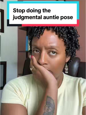 A selfie with a woman, seen from the chest up, covering her mouth with one hand. She has dark curly hair and is wearing a light yellow top with a tattoo of a bird on her left forearm. The background includes wooden trim and a bookshelf. A text overlay at the top says, 'Stop doing the judgmental auntie pose'.