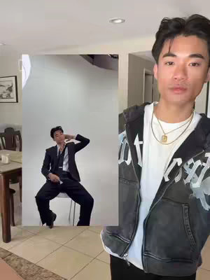 The cover image shows a man on the right side of the frame in front of a gray interior background. On the left side, there is a mock photo studio scene with the same man, dressed in a suit, posing in front of a white backdrop. The man in the foreground is wearing a black hoodie with white text, a white t-shirt, and multiple necklaces. He is looking at the camera.