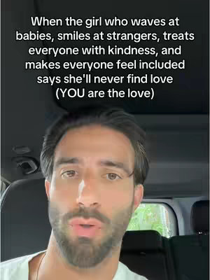 A man is filmed from the chest up, talking to the camera from the driver's seat of a vehicle. Text is overlaid on the image.