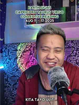 A man with short, spiky silver hair and a red jacket is centered in the frame, smiling and speaking into a microphone. Text overlays provide context, including the zodiac readings.
