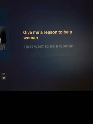 The image is a screenshot of a video with dark background. Text overlays in a light color are present. The lower part of the image is solid black. The top text says 'Give me a reason to be a woman' and the bottom text says 'I just want to be a woman'.
