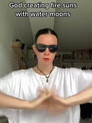 A person in front of a blurry background wearing sunglasses and a white shirt is shown with their hands together in a prayer-like position. The person is also wearing a necklace and has red lipstick on.