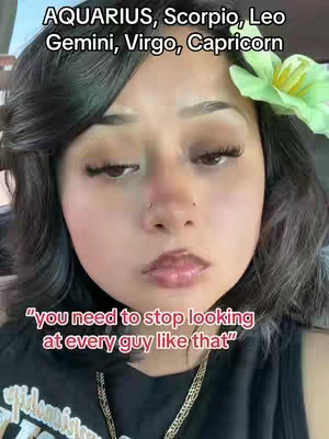 A young woman with dark hair and a flower in her hair is looking directly at the camera with an expression of slight annoyance. Above her head is text that reads: "AQUARIUS, Scorpio, Leo
Gemini, Virgo, Capricorn". The text overlayed on the bottom of the frame reads "you need to stop looking
at every guy like that".