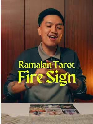 A man with short black hair smiles while looking off-camera, layered over a background of wooden panels. Bold text with a yellow fill sits on top of the image, reading "Ramalan tarot" wrapping over "Fire Sign". In the bottom, partial glimpses of what appears to be tarot cards are visible.