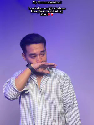 A man is shown in the center of the frame, covering his mouth with his hand. He has short dark hair and is wearing a light blue and white checkered shirt. The background is a gradient of purple. Text overlays the image at the top, describing his current emotional state.