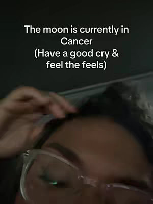 A selfie-style image featuring the upper portion of a person's face, with focus on their eyes and forehead area. They are wearing clear-framed glasses and have their hand near their hair. Text overlayed on the image, is written in a clean, sans-serif font, providing astrological insight with a call to action.