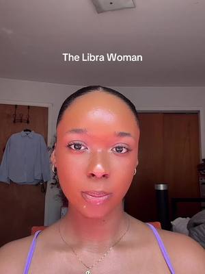 A close-up shot of a woman's face with her hair pulled back. The image is evenly lit, with a soft red hue at the top of the forehead. The words "The Libra Woman" appear at the top of the image.