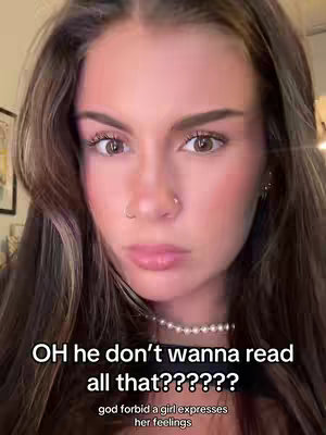 A close-up shot of a young woman's face. She has long brown hair with highlights, brown eyes, and a small nose ring. She is wearing a pearl necklace. Text overlays with a black background and white font are present, with the main text reading, "OH he don't wanna read all that??????" and the smaller text below it saying, "god forbid a girl expresses her feelings."