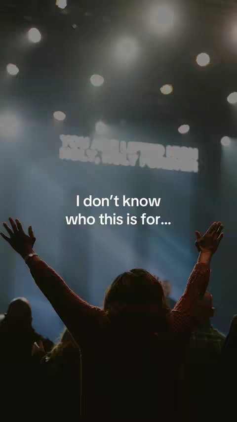 A vertical image shows a person from the back with their arms upraised, seemingly in a worshipful gesture. The person is silhouetted against a bright light, possibly from stage lighting. The background is dark, with visible lights creating a sense of depth and atmosphere. Text overlayed is white, positioned over the center of the image.