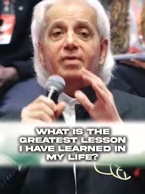 An older man with white hair and a dark suit is holding a microphone and speaking. A text overlay at the bottom asks, "WHAT IS THE GREATEST LESSON I HAVE LEARNED IN MY LIFE?"