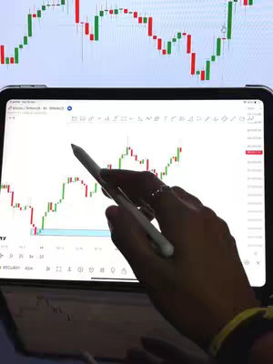 The cover image shows a person's hand holding a stylus and pointing to a chart on a tablet. The tablet displays a line graph with red and green candlesticks, indicating stock or financial data. Above the tablet, a larger display shows a separate graph with similar candlestick patterns. The color scheme is dominated by white and shades of green and red found in the trading indicators.