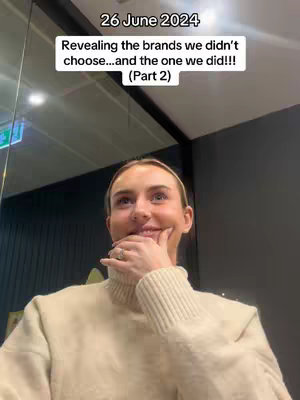 A medium shot shows a woman with fair skin, dark hair pulled back, and a cream-colored turtleneck. She is looking up and to her right with a slight smile, her right hand touching her chin. Text overlayed on the top describes the video topic.