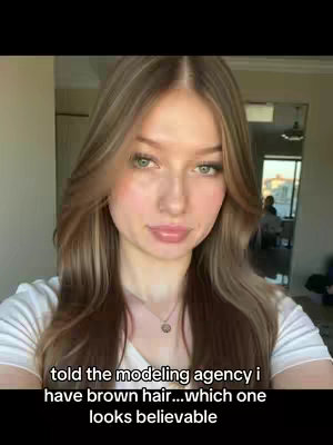 The cover image features a woman in a close-up selfie. She has long, wavy light brown hair with blonde highlights framing her face. She has fair skin, a gentle smile, and is wearing a white t-shirt. Behind her is a room with a view and light coming in. The text overlay indicates this video includes a question about hair color.