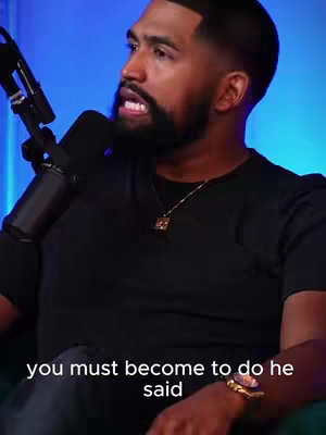 A man wearing a black shirt speaks into a microphone. The background is blue. Text is overlaid at the bottom.