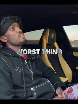 A man in a black hoodie and a black headband looking up, seated inside a car. The car's interior has black and gold accents. The text overlay says 'WORST THING'.