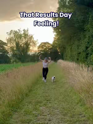 A cover image shows a woman running on a grassy path with her hands up in the air, as if celebrating. A small dog is running in front of her. The path is lined with tall grass on either side, and trees and a sunset sky are in the background. Text overlayed states "That Results Day Feeling!"