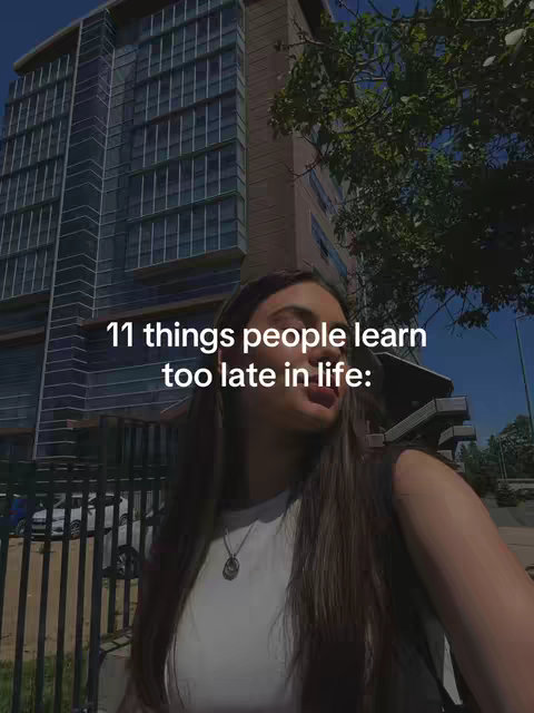 A woman is shown with long brown hair and a white shirt, outdoors with a city building in the background, with the text overlayed on the image. The woman is looking away from the camera, her tongue sticking out slightly.