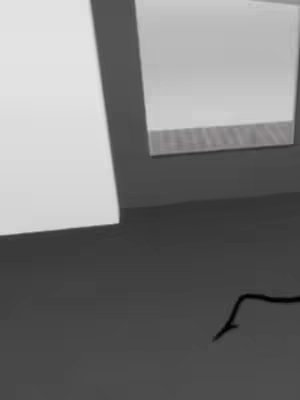 An abstract image featuring a dark gray surface in the foreground, with a few white elements and a glimpse of a light-colored wall. The layout appears minimalistic, with a dark-to-light contrast.