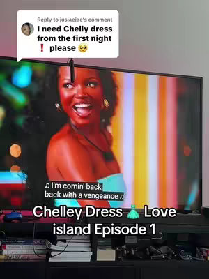A television screen displays a scene from Love Island USA featuring a woman with dark hair and a strapless turquoise top, smiling and looking offscreen. Overlayed text comments are positioned in the top right of the screen.